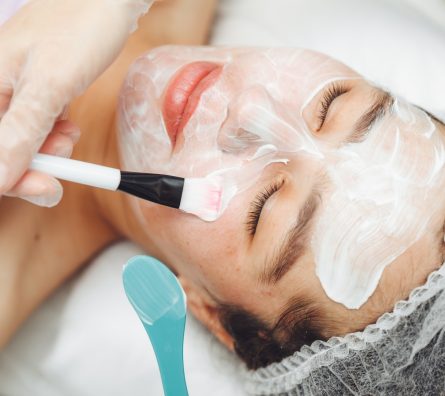 A cosmetologist does facial care and apply a face mask. A cosmetologist does facial care and apply a face mask.