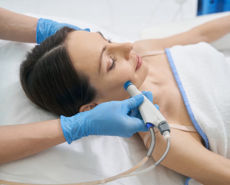 Beauty therapist performing hydrafacial procedure on woman