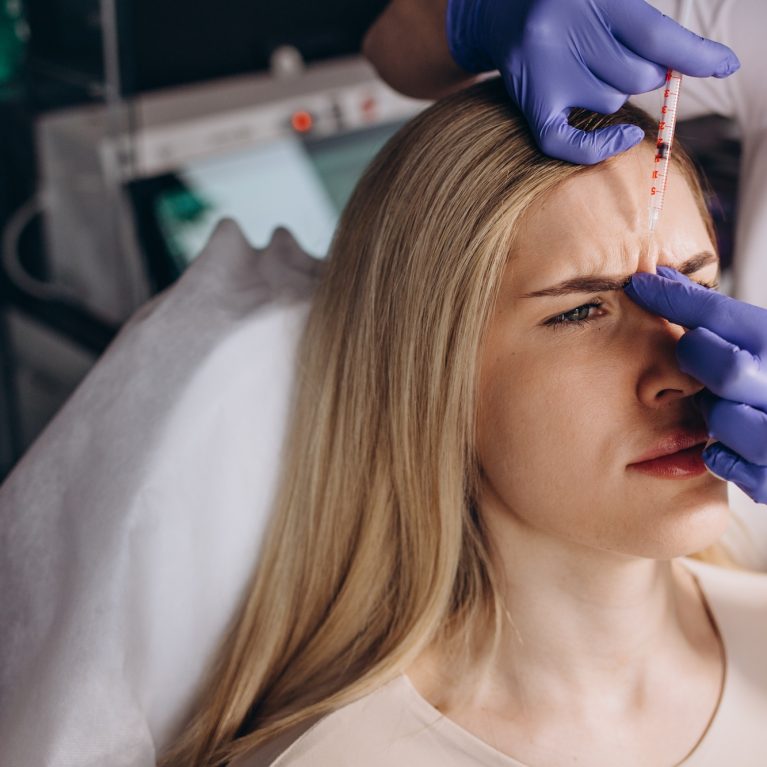 Close up of botox injection in the eyebrow or forehead of female patient