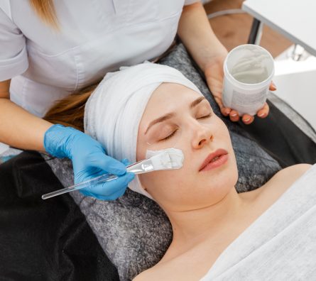 Cosmetician giving client facial skincare mask. Beautician working Cosmetician giving client facial skincare mask. Beautician working