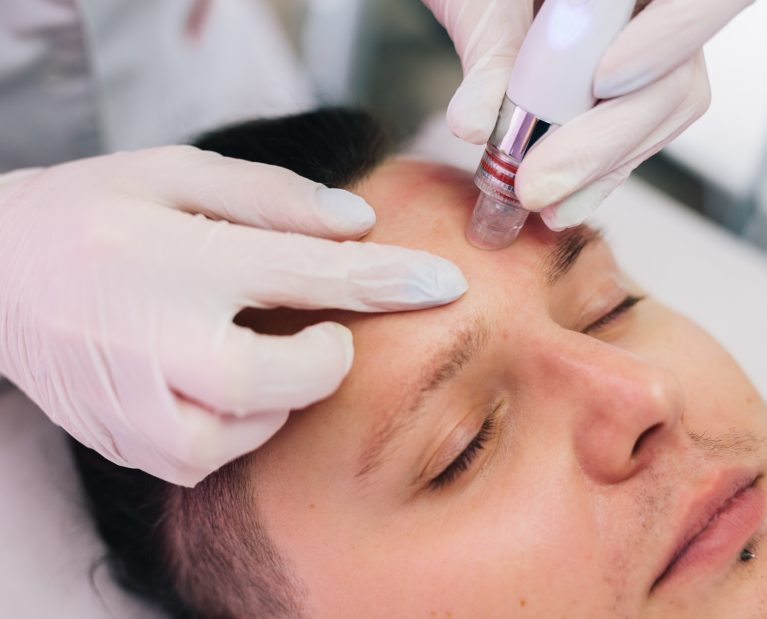 Cosmetologist doing hydrafacial treatment on man face