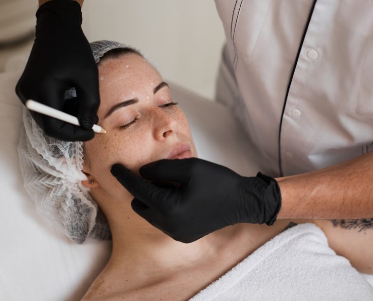 cosmetologist marking skin of caucasian woman with pencil.